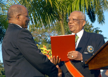 Former Governor-General, His Excellency the Most Hon. Sir Howard Cooke (right), presents the instruments of office to new Governor-General, His Excellency the Most Hon. Kenneth Hall.