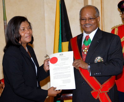 Chief Justice Zaila McCalla (left), shows her instrument of appointment as Head of Jamaica's Judiciary, shortly after Governor General His Excellency the Most Honourable Professor Kenneth Hall (right), presented it to her at the official swearing ceremony, held at King's House on June 26. 