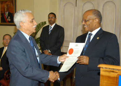 Governor General, His Excellency, the Most Hon. Professor Sir Kenneth Hall (right), presents Colonel Trevor MacMillan with his Instrument of Office as the new Minister of National Security, during a brief swearing in ceremony at King’s House, today (May 13). Col. MacMillan, who takes over the portfolio previously held by Derrick Smith, was also sworn in as a Government Senator in the Upper House. Looking on at left is Prime Minister Bruce Golding.