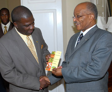 Governor-General, His Excellency the Most Hon. Professor Sir Kenneth Hall (right), accepts a brochure containing information about the Certification of Agricultural Produce Programme from Senator Norman Grant, President of the Jamaica Agricultural Society (JAS), during a call on the Governor-General on October 15, at King's House.