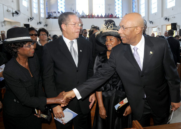 The Governor-General, His Excellency the Most Hon. Sir Patrick Allen reaches across to greet the wife of the Prime Minister, the Hon. Bruce Golding, Mrs. Lorna Golding, at the start of today's (August 8) funeral service for the late Lady Bustamante at the Sts. Peter and Paul Roman Catholic Church, Kingston. Looking on are: Mr. Golding(second left); and the wife of the Governor-General, Lady Patricia Allen(second right).