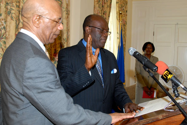 Governor-General, His Excellency the Most Hon. Sir Patrick Allen (left), looks on as Bishop Herro Blair takes the Oath of Office and Oath of Allegiance as Political Ombudsman for another five years, during a re-appointment ceremony, held at King's House, today (August 25. At right is the Governor-General's Secretary, Dionne Tracey Daniels.