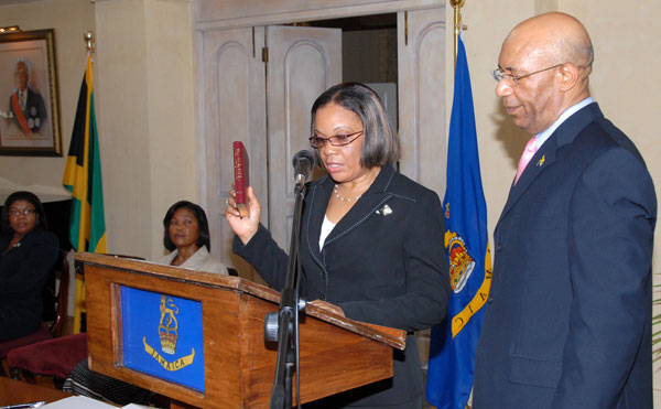 Governor-General, His Excellency the Most Hon Sir Patrick Allen (right) looks on as Her Honour Miss Carol Edwards (second right) takes the Oath of Office and Judicial Oath to act as a Puisne Judge, during a ceremony at King's House on Monday (September 7). Sharing in the moment are the wife of the Governor-General, Her Excellency the Most Hon. Lady Allen (seated second left) and Chief Justice, Hon. Mrs. Zaila McCalla, both seated at left.