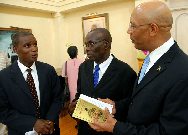 Governor-General, His Excellency the Most Hon. Sir Patrick Allen (right), discusses the contents of the Students' Motivational Manual with its author, Archibald Edwards (centre) and Publishing Director at the West Jamaica Conference of Seventh Day Adventists, Pastor Rohan Sewell , at the official launch of the handbook, at King's House, on August 17.