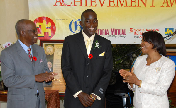 Mr. Nicholas Powell, graduate of the University of Technology (UTech), and a recipient of the Governor General's National Youth Award of Excellence for 2009 (centre), is applauded by Her Excellency the Most Hon. Lady Allen, wife of the Governor-General and Custos of Manchester, Hon. Dr. Gilbert Allen, at the presentation ceremony, which took place at King's House on November 11.