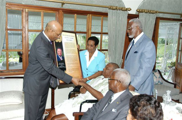 Governor General, His Excellency the Most Hon. Sir Patrick Allen (left) presents a citation to retired Custos of St. James, Hon. Clarence Nelson (seated 3rd right), at his home in Anchovy St. James last week. Sharing the moment are Custos Nelson's wife Lucille Nelson (standing 2nd left); former Acting Custos Enel Brydson (standing 3rd left); Custos of St. James Hon. Ewen Corrodus (seated 2nd right) and wife Daphne Corrodus.