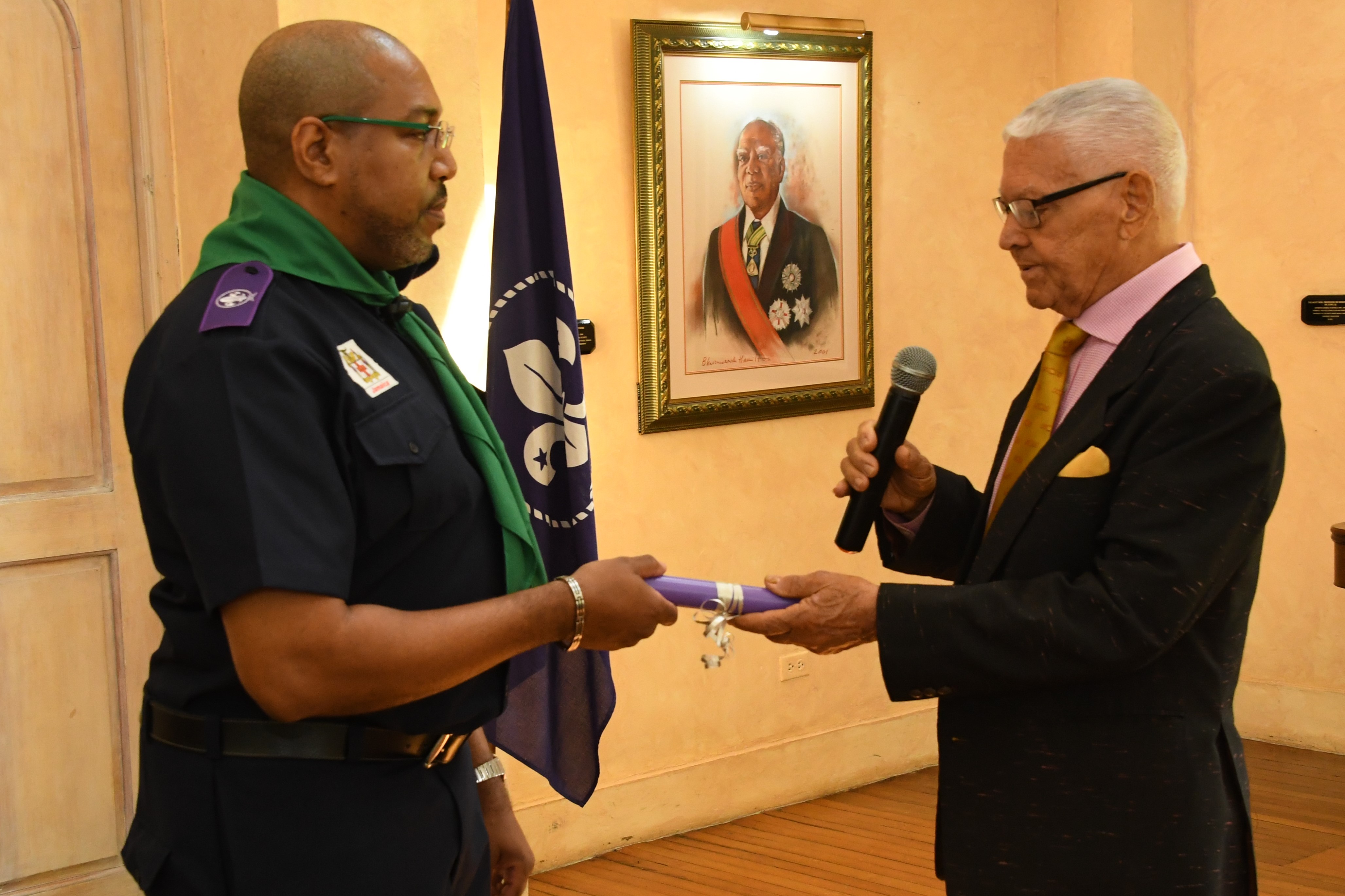Changing of the Guard as outgoing President the Honourable Oliver Jones passes the baton to Mr. Richard Simpson, newly appointed President of the Scout Association of Jamaica.