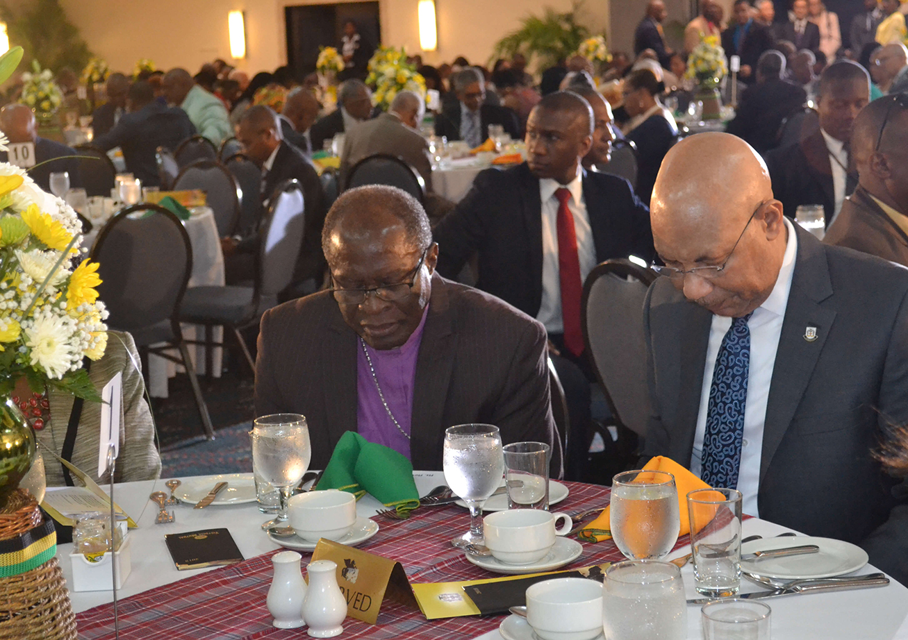 Sir Patrick Allen (r) and Reverend Stanley Clarke pray during the National Leadership Prayer Breakfast on Thursday (Jan 18).